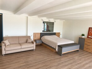 Un dormitorio moderno con una cama, un sofá, una mesita de noche y un aparador.