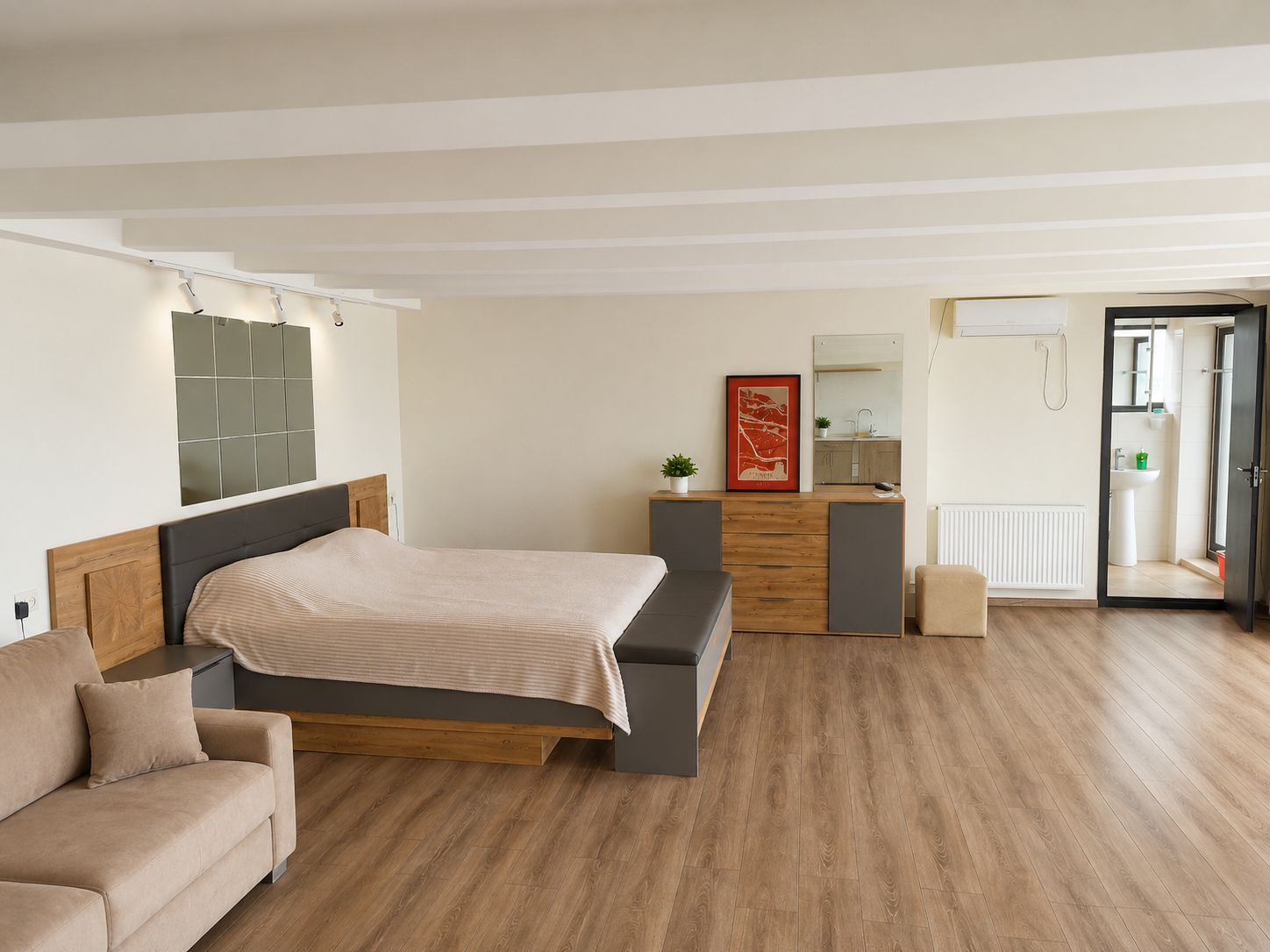 A modern bedroom with a bed, a sofa, a dresser, and a bathroom visible through an open door.