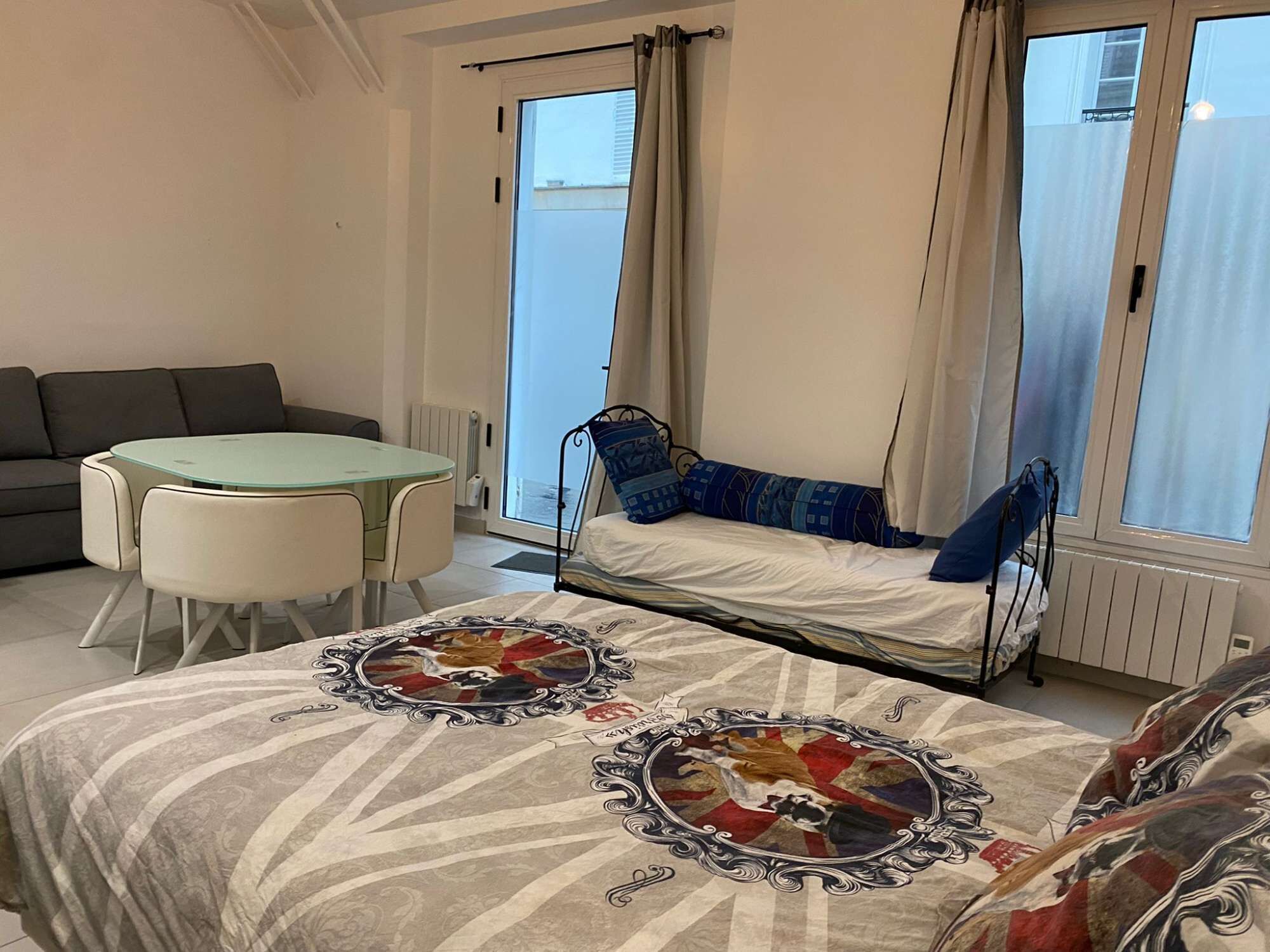 Une pièce comprenant un lit, un canapé, une table ronde et une fenêtre avec des rideaux.