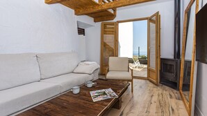 A cozy living area with a wooden ceiling, a sofa, a coffee table with a magazine, and a fireplace. - Country house 15 minutes from the beach (Málaga)