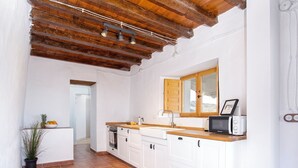 A kitchen with white cabinets, a wooden countertop, a built-in microwave, and a window with a wooden shutter. - Country house 15 minutes from the beach (Málaga)