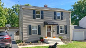 A two-story house with a front porch, a garage, and a dog on the lawn.