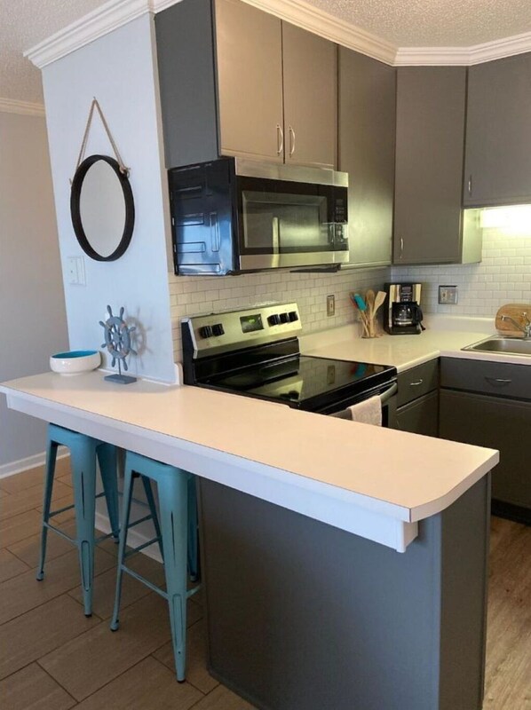 A modern kitchen with a central island, stainless steel appliances, and a nautical-themed wall decor.