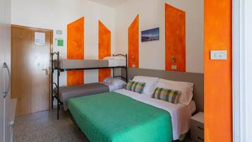 Habitación individual con una cama individual sobre otra, un edredón verde y paredes de acento naranja.