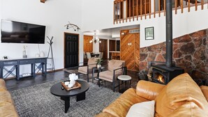 Ein Wohnzimmer mit Fernseher, Sofa, Couchtisch, Kamin und einer Treppe.