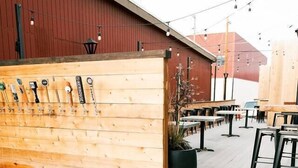 Eine Holzterrasse mit Außenmöbeln, einem an der Wand befestigten Werkzeughalter und einem Blumentopf.