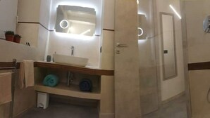 A modern bathroom with a large mirror, a sink, and a towel rack.