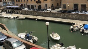 A marina with boats docked, a red car in the foreground, and buildings in the background.
