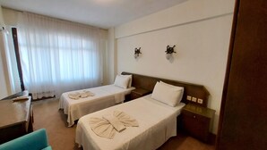 A hotel room with two single beds, a desk, and a chair. - Orkide Otel (Didim)
