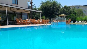A swimming pool with lounge chairs and a sunshade, surrounded by trees and a building. - Orkide Otel (Didim)