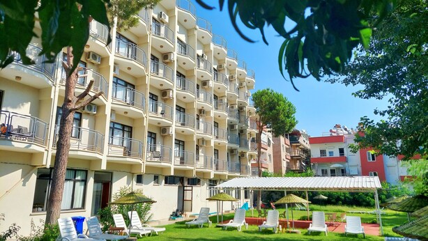 A multi-story hotel with balconies, outdoor seating, and a garden area. - Orkide Otel (Didim)
