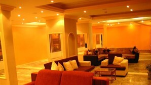 A spacious lobby with multiple seating areas, including a red sofa and a brown sofa. - Orkide Otel (Didim)