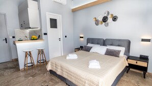 Une chambre à coucher comprenant un lit, des tables de chevet, une commode, un petit bureau avec des tabourets et un luminaire fixé au mur.