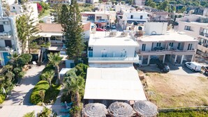 Un quartier résidentiel avec une maison à deux étages dotée d’un balcon, d’une allée et d’un petit jardin agrémenté de palmiers.