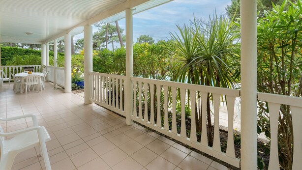 A covered patio area with white railings, a tiled floor, and outdoor furniture. - Swimming pool villa for 8 in Lacanau (Lacanau)