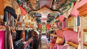 A cozy, ornate room with a fireplace, plush seating, and a decorative ceiling.
