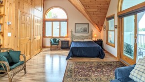 Une chambre spacieuse avec un grand lit, un ventilateur de plafond et une vue sur l’extérieur grâce à une grande fenêtre.