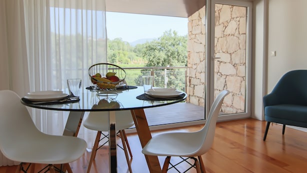 A dining area with a glass table, white chairs, and a fruit bowl.