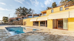 A modern house with a swimming pool, stone patio, and large windows.