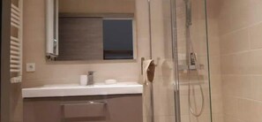 Een douche, handdoeken, zeep, toiletpapier