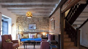 Un intérieur rustique avec un mur en pierre, un escalier en bois et un canapé bleu.