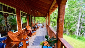 A covered wooden deck with seating, a fan, and a potted plant.