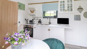 A compact kitchen with white cabinets, a built-in oven, a sink, and a window above the countertop. - High Rigg Shepherd's Sunrise (Brampton)