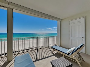 A balcony with a view of the beach, a door, and a lounge chair. - Beachfront Views, Pools! (Orange Beach)