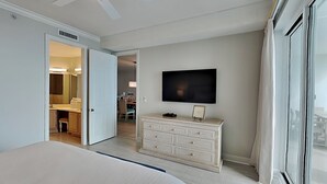 A bedroom with a bed, a dresser, a TV, and a ceiling fan.