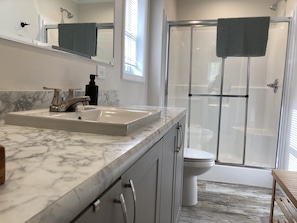 A modern bathroom with a marble sink, a glass shower enclosure, and a toilet. - Escanaba River Escape-The Birch Tree Home   Modern 3BR Riverfront Retreat (Gladstone)