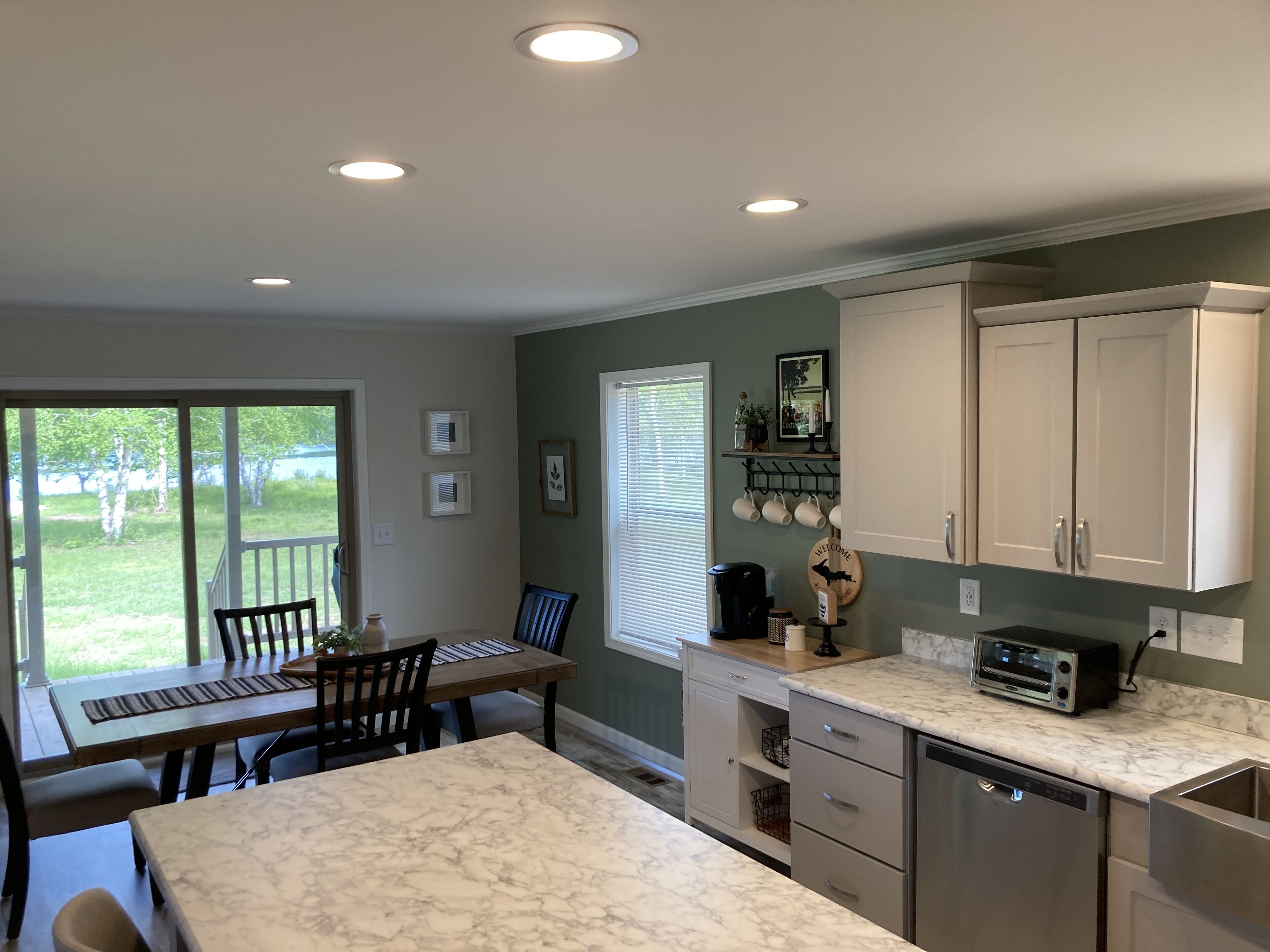 A kitchen with a marble countertop, a coffee maker, and a toaster. There is a dining area with a table and chairs.