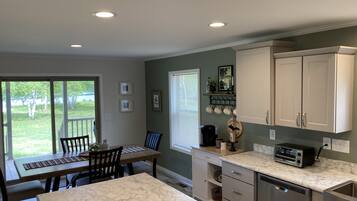A kitchen with a marble countertop, a coffee maker, and a toaster. There is a dining area with a table and chairs.