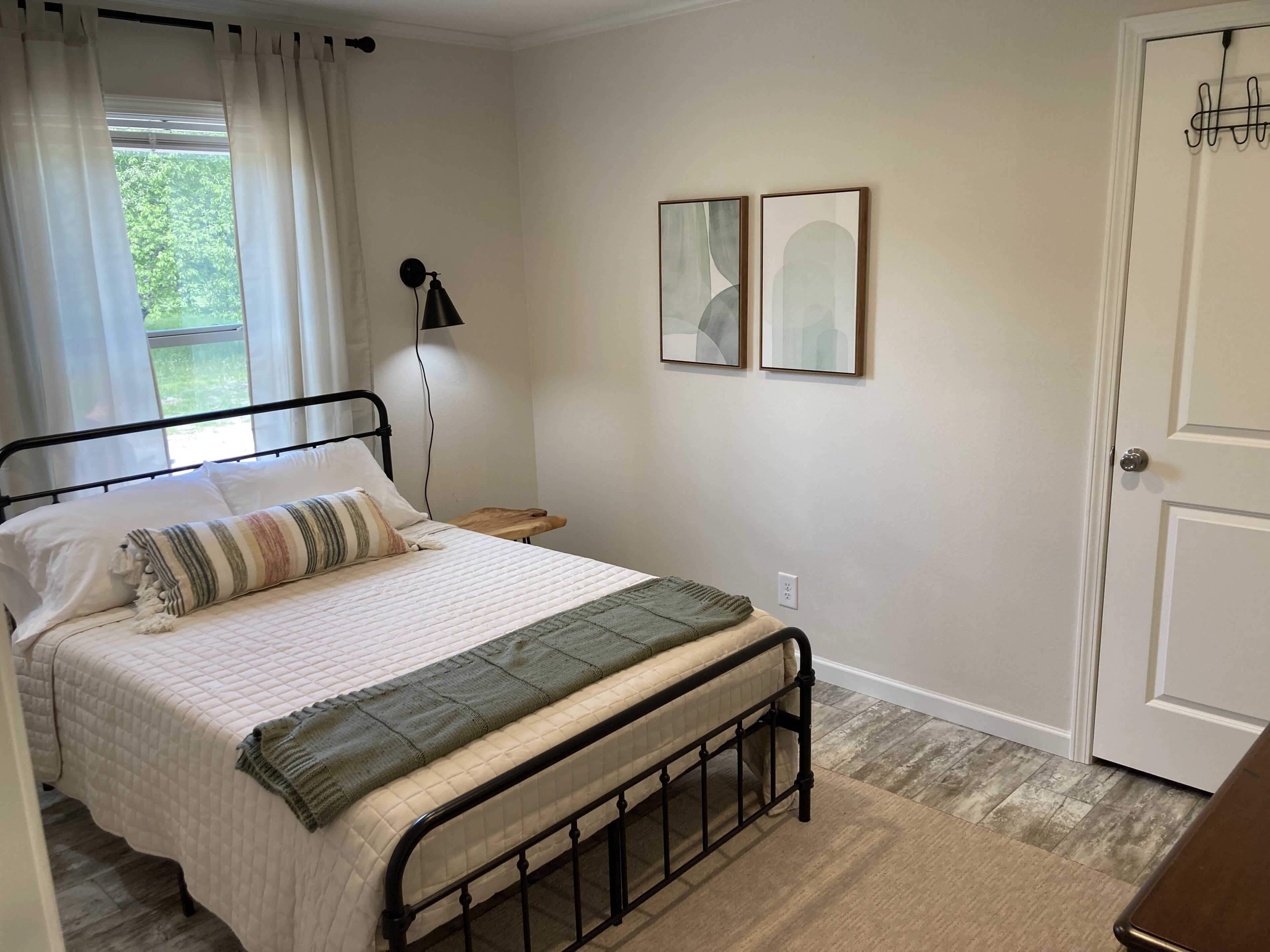 A neatly arranged bedroom with a bed, bedside table, lamp, and two framed pictures on the wall.
