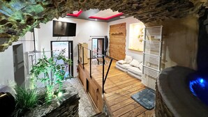 A modern interior with a wooden staircase, a flat-screen TV, and a seating area with cushions. - Troglodyte Jacuzzi in the City Centre, nearby the beach, Patio, A/C, WiFi (Collioure)