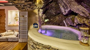 A spa area with a stone wall, a hot tub, and a wooden bench. - Troglodyte Jacuzzi in the City Centre, nearby the beach, Patio, A/C, WiFi (Collioure)