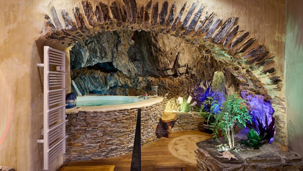 A spa area with a stone wall, a wooden bench, a small table, and a bathtub. - Troglodyte Jacuzzi in the City Centre, nearby the beach, Patio, A/C, WiFi (Collioure)