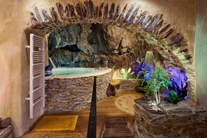 A spa area with a stone wall, a wooden bench, a small table, and a bathtub. - Troglodyte Jacuzzi in the City Centre, nearby the beach, Patio, A/C, WiFi (Collioure)