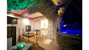 A spa room with a stone wall, a bed, a small pool, and a wooden deck. - Troglodyte Jacuzzi in the City Centre, nearby the beach, Patio, A/C, WiFi (Collioure)
