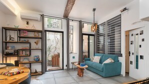 A modern living room with a teal sofa, a wooden coffee table, and a bookshelf filled with books and decorative items. - Troglodyte Jacuzzi in the City Centre, nearby the beach, Patio, A/C, WiFi (Collioure)
