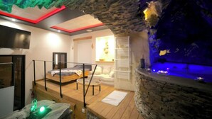 A spa room with a stone wall, a bed, a small pool, and a wooden deck.