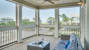 Ein überdachter Balkon mit Deckenventilator, einem Rattan-Sofa und einem kleinen Tisch.