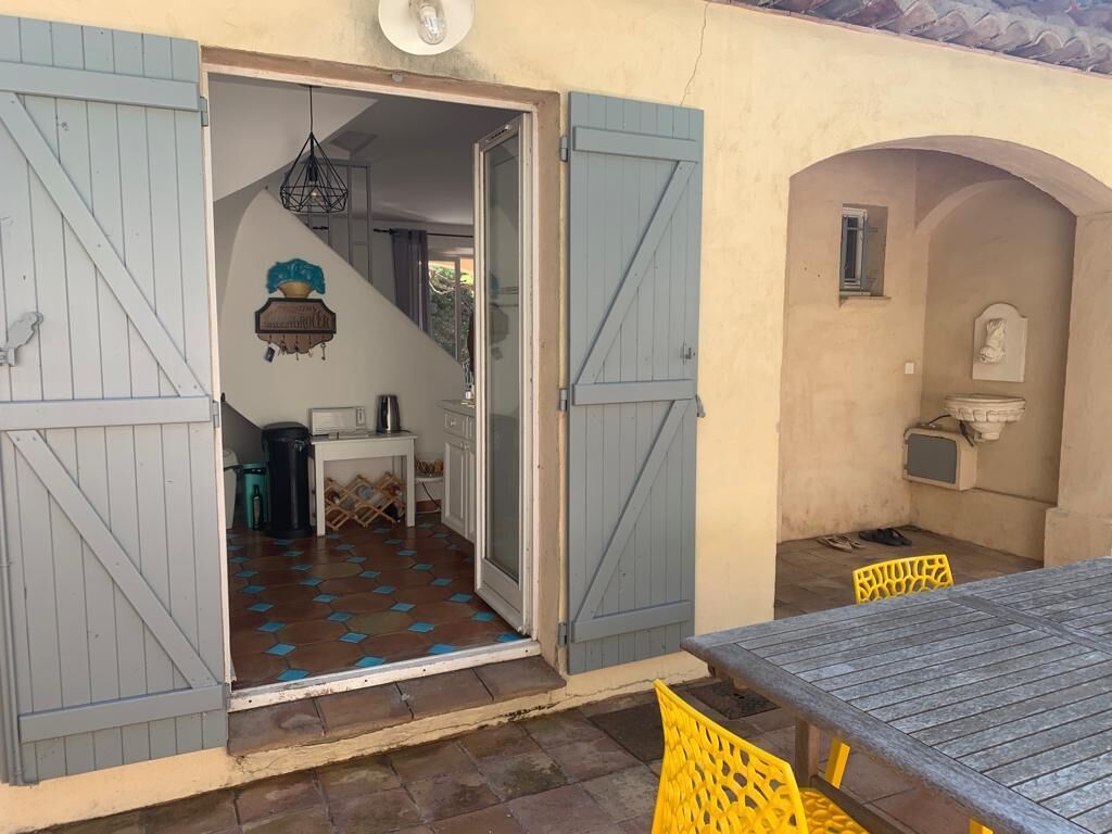 Una habitación con piso de baldosas, una mesa, sillas y una lámpara colgante.