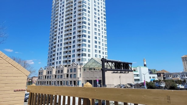 Un edificio moderno y esbelto con varios balcones y un cielo azul despejado.