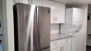 Una cocina con electrodomésticos de acero inoxidable, armarios blancos y encimera de granito.