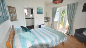 Une chambre avec un lit, un plancher en bois, une salle de bain avec douche et une vue sur l’extérieur.
