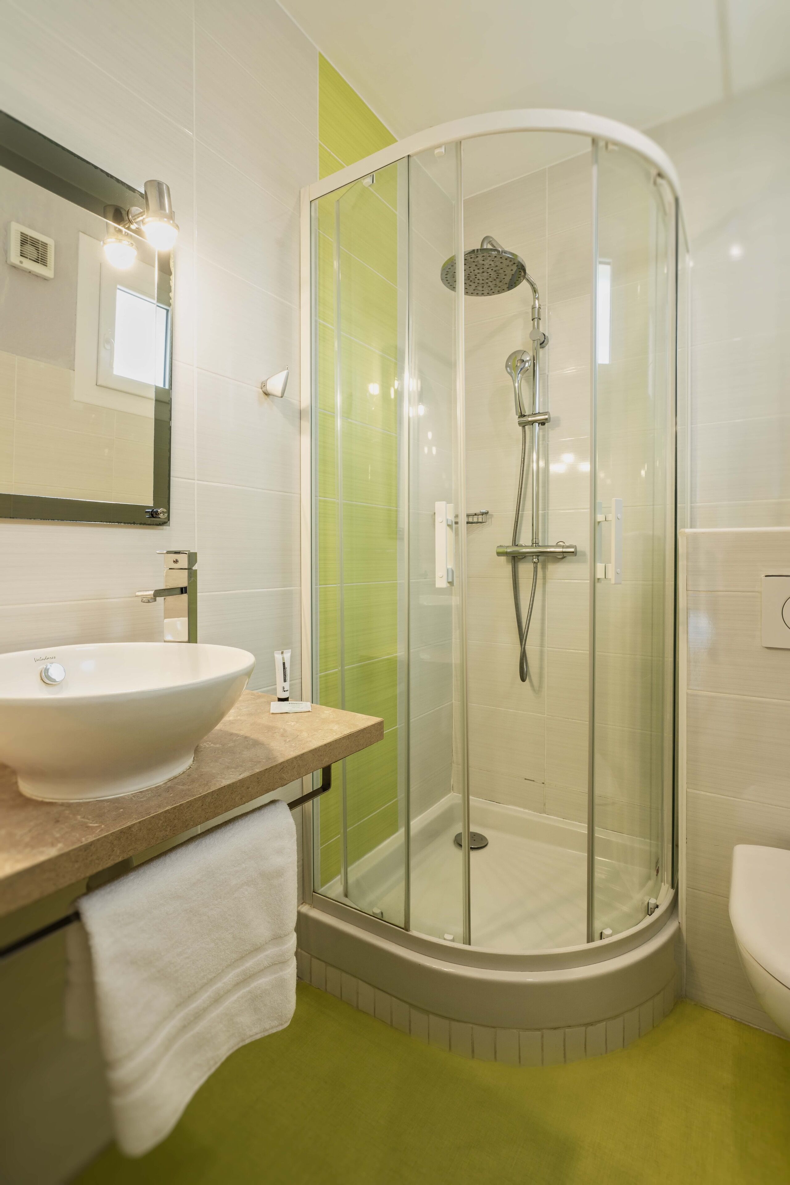 Un baño moderno con ducha de vidrio, lavamanos blanco y un inodoro.