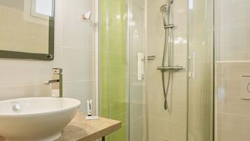 Un baño moderno con ducha de vidrio, lavamanos blanco y un inodoro.
