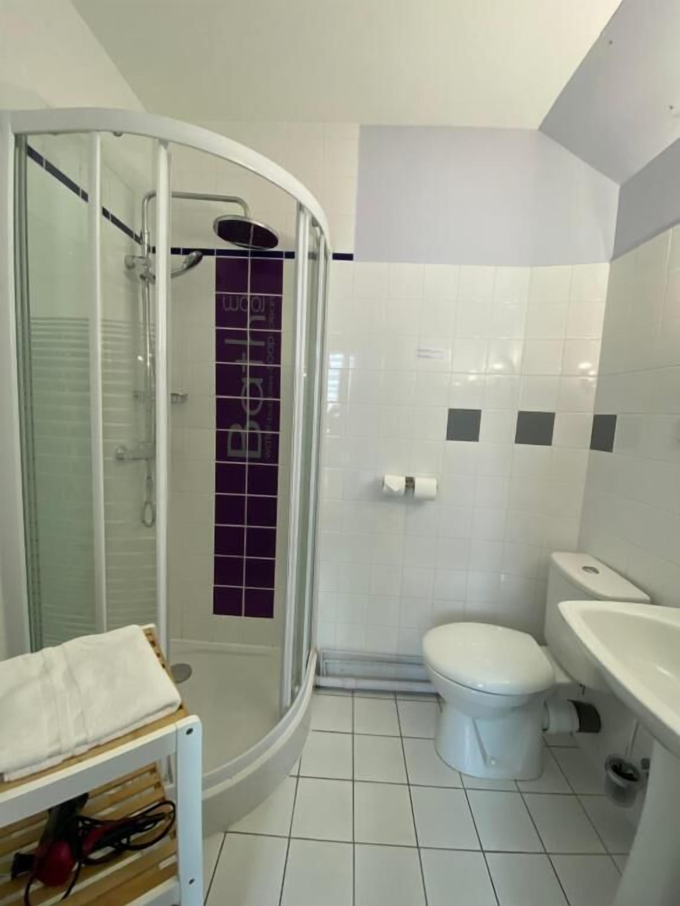Un baño con ducha de vidrio, inodoro blanco y lavamanos.