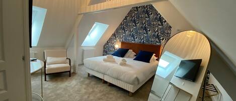 A bedroom with a bed, a chair, a desk, and a large window.