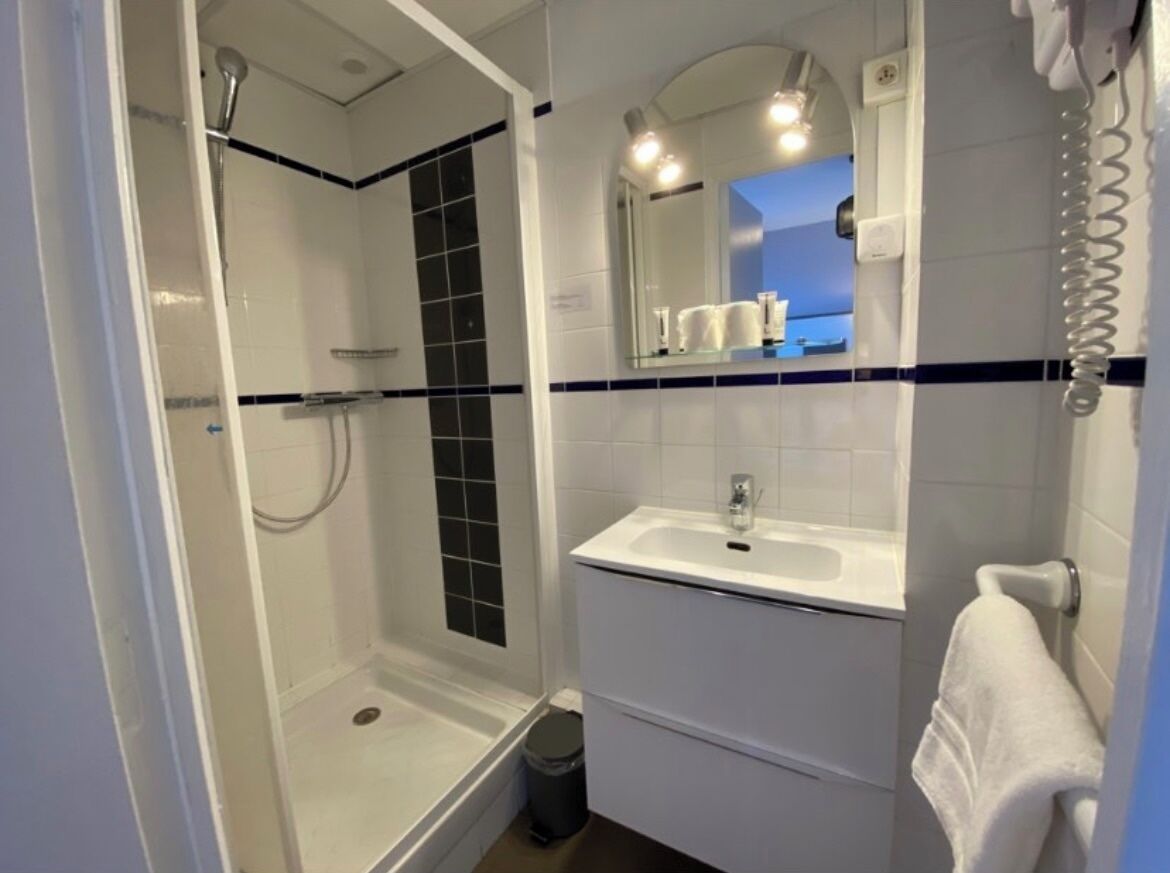 Ein Badezimmer mit Dusche, Waschbecken und Spiegel.